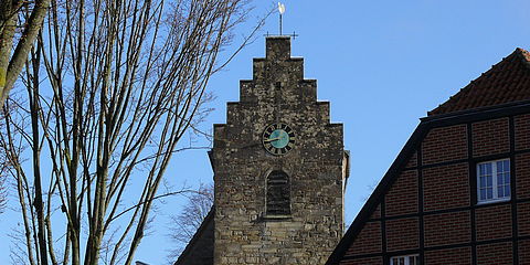 Sandstein-Kirchturm von vorne, rechts im Bild ein Teil des Giebels der Alten Diele.